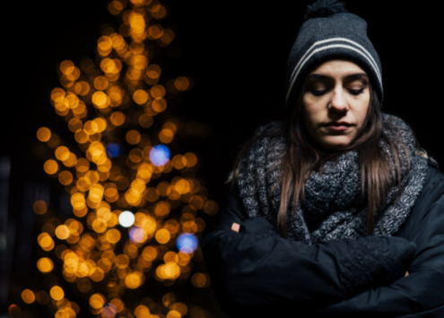 Woman walking alone looking sad, highlighting the theme of loneliness and mental health challenges during the festive season.