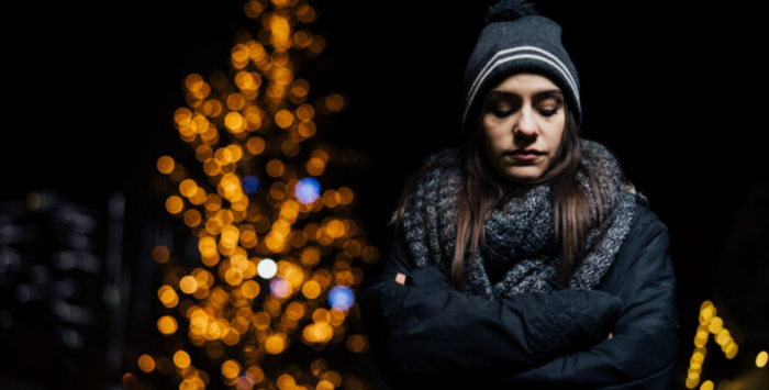 Woman walking alone looking sad, highlighting the theme of loneliness and mental health challenges during the festive season.