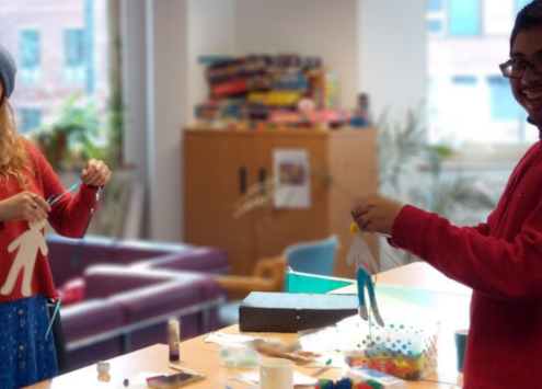 Service user and support worker smile while making Christmas crafts for charity tree.