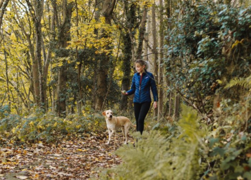 Woman walking a dog in a forest.