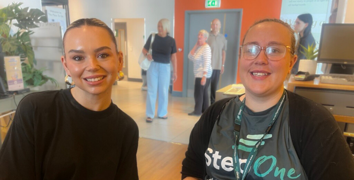 Two women sat down and smiling