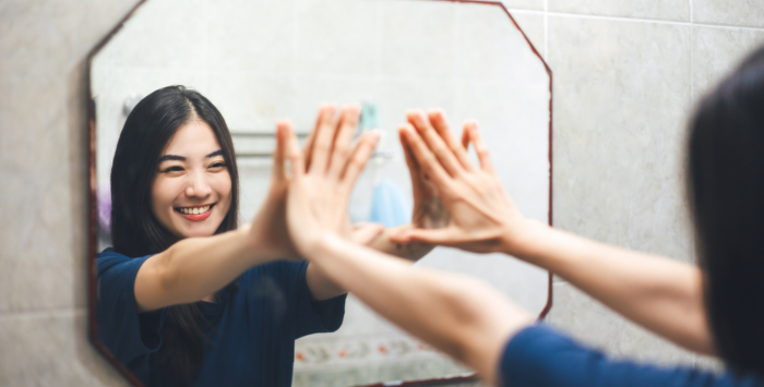 Woman looking in the mirror with her hands up against it